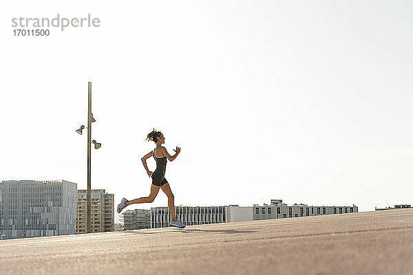 Weibliche Sportlerin beim Joggen an einem sonnigen Tag in der Stadt