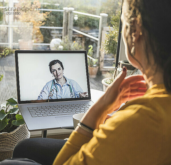 Lächelnde Ärztin auf dem Laptop-Bildschirm während eines Videoanrufs