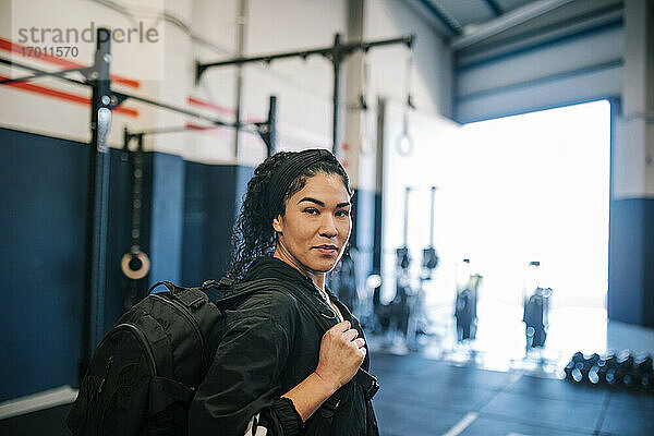 Selbstbewusste Sportlerin mit Rucksack im Fitnessstudio