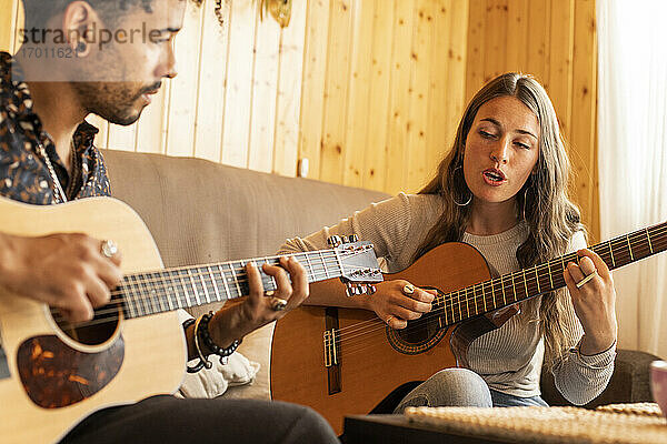 Frau singt beim Gitarrenspiel mit Mann zu Hause