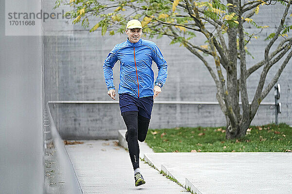 Älterer Mann mit Mütze joggt auf dem Fußweg