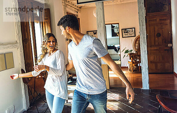 Junges Paar tanzt im Wohnzimmer zu Hause