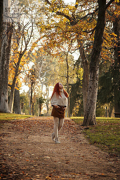 Frau geht im Herbst auf einem Fußweg im Park spazieren