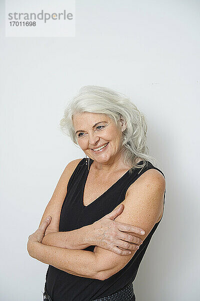 Lächelnde ältere Frau  die sich vor weißem Hintergrund umarmt