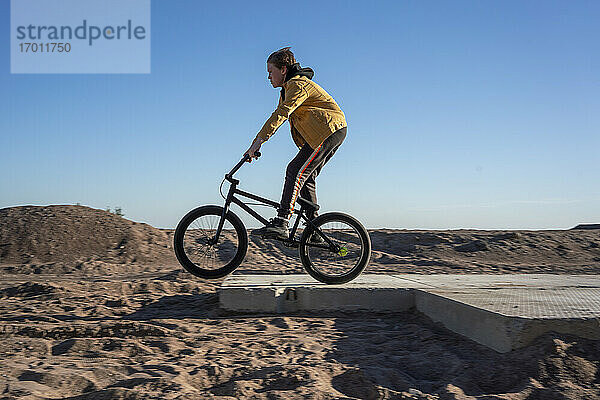 Junge fährt BMX auf Sand