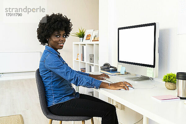 Junge Frau arbeitet am Computer  während sie zu Hause sitzt
