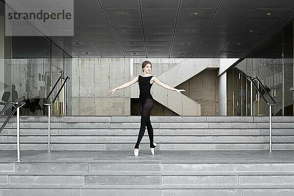 Ballerina in schwarzem Trikot in modernem Betongebäude