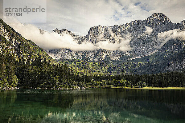 See und wolkenverhangene Berge