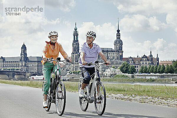 Älteres Paar fährt mit dem Elektrofahrrad auf der Straße am Hausmannsturm  Dresden  Deutschland