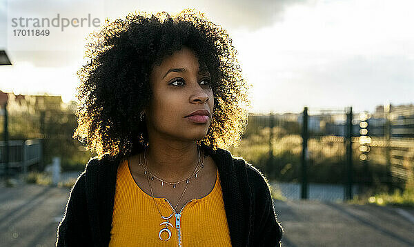 Nahaufnahme einer nachdenklichen schönen Frau mit Afro-Haar gegen den Himmel
