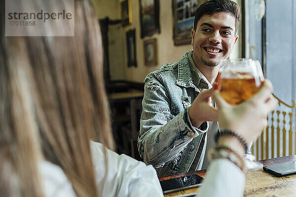 Glückliche Freunde  die lächelnd in einer Bar auf Getränke anstoßen