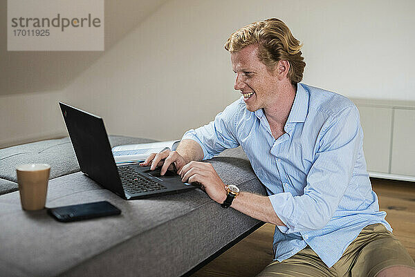 Lächelnder Geschäftsmann arbeitet zu Hause am Laptop