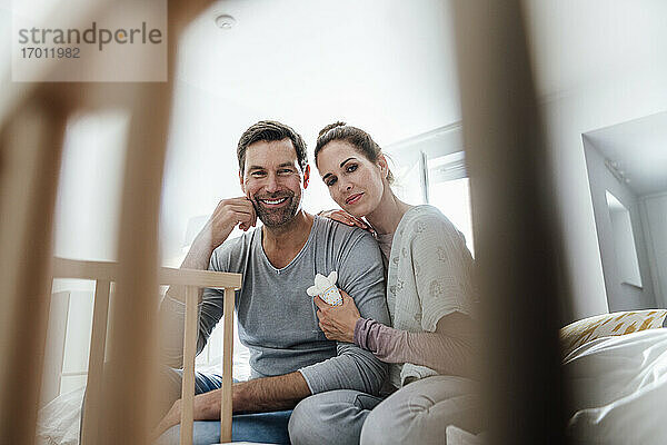 Lächelndes Paar  das die Krippe im Schlafzimmer einer Wohnung betrachtet