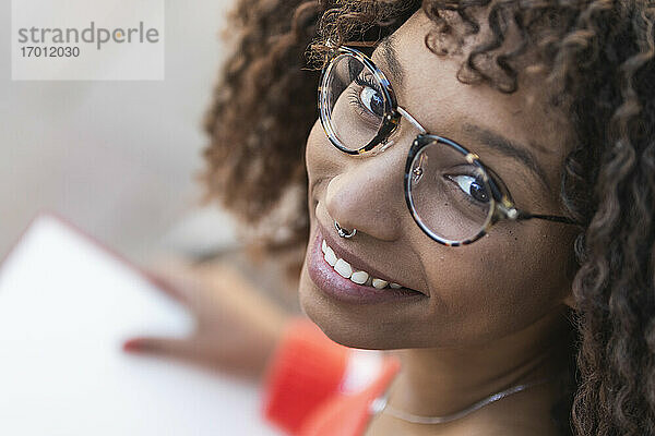 Lächelnde Afro-Frau mit Brille und Buch