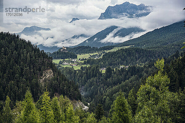 Schweiz  Kanton Graubünden  Scuol  Grünes bewaldetes Tal mit Schloss Tarasp im fernen Hintergrund