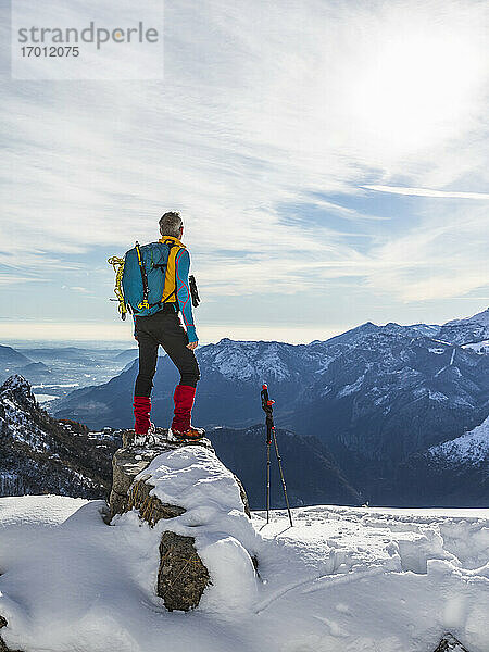Männlicher Wanderer mit Rucksack  der die Aussicht betrachtet  während er auf dem Gipfel eines Berges steht  Orobische Alpen  Lecco  Italien