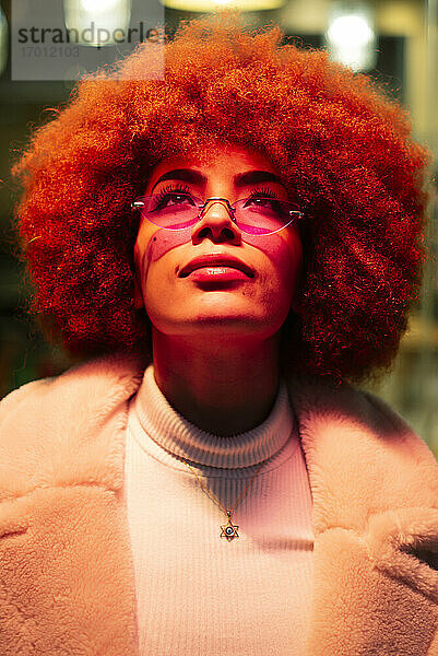 Nahaufnahme einer stilvollen Frau mit Afro-Haar  die eine Sonnenbrille trägt und nach oben schaut