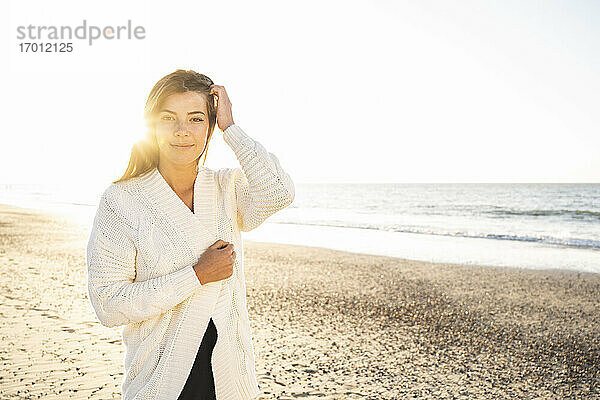 Schöne Frau steht am Strand gegen den klaren Himmel an einem sonnigen Tag