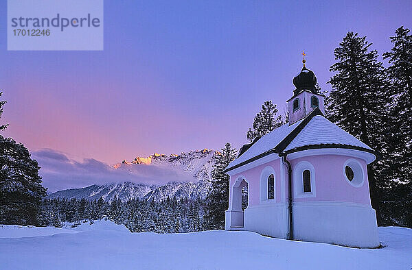 Kapelle auf schneebedecktem Land gegen den Himmel bei Sonnenuntergang