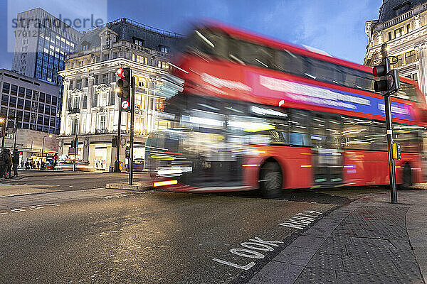 UK  London  Roter Doppeldeckerbus überquert Oxford Circus Kreuzung bei Nacht  unscharf