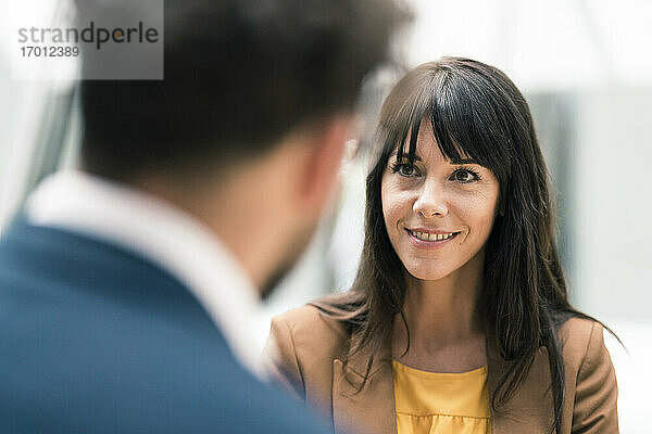 Lächelnde Unternehmerin betrachtet einen männlichen Kollegen im Büro