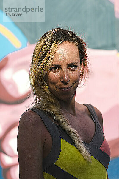 Mid erwachsene Frau mit blondem Haar gegen grafittin Wand auf sonnigen Tag