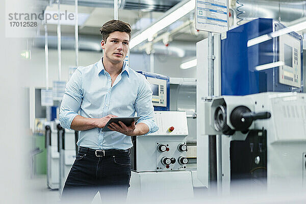 Junger Geschäftsmann mit digitalem Tablet bei der Arbeit in der Industrie
