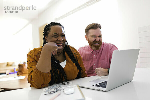 Lächelnde Mann und Frau Blick auf Laptop am Schreibtisch im Home-Office