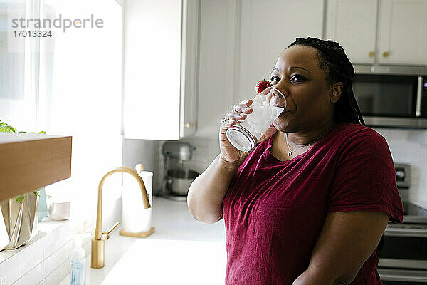 Frau trinkt Wasser in der Küche