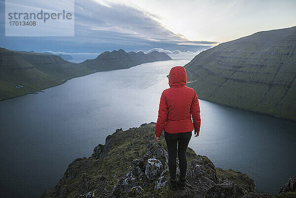 Dänemark  Färöer Inseln  Klaksvik  Frau steht auf dem Gipfel des Berges Klakkur über dem Meer und schaut auf die Aussicht