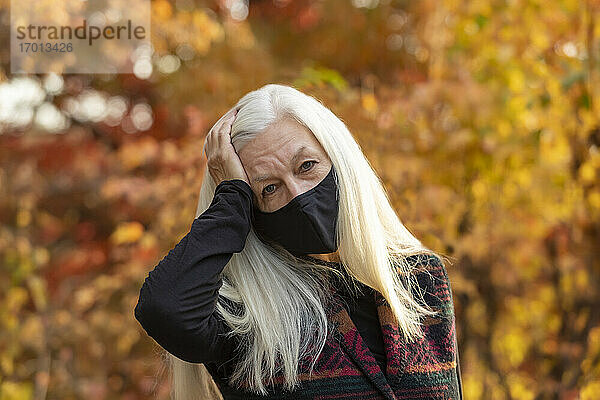 Porträt einer älteren Frau mit Covid-Schutzmaske im Freien im Herbst