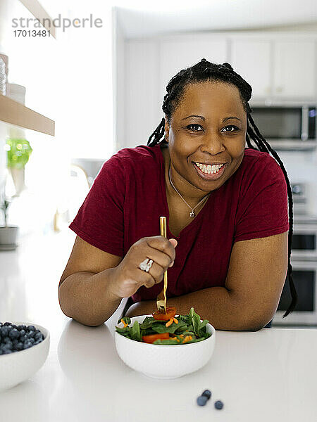 Porträt der lächelnden Frau mit gesunden Salat in der Küche