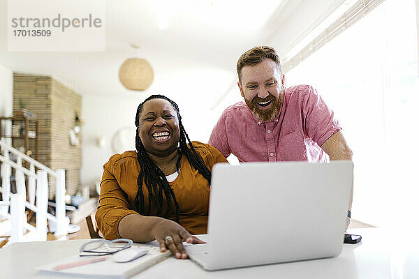 Mann und Frau schauen auf Laptop am Schreibtisch im Home-Office