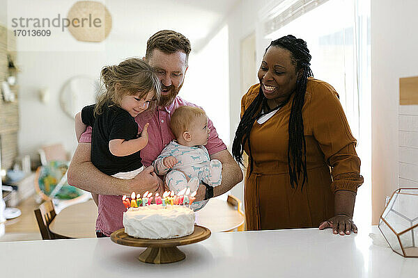 Frau und Mann mit Kindern (2-3  9-11 Monate) feiern Geburtstag zu Hause