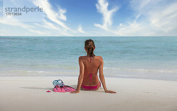 Malediven  Rückansicht einer Frau im Bikini  die am Strand sitzt