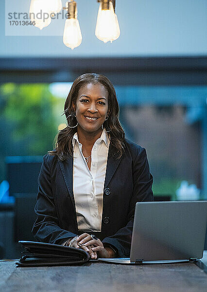 Porträt der lächelnden Geschäftsfrau sitzt am Schreibtisch mit Laptop im Büro