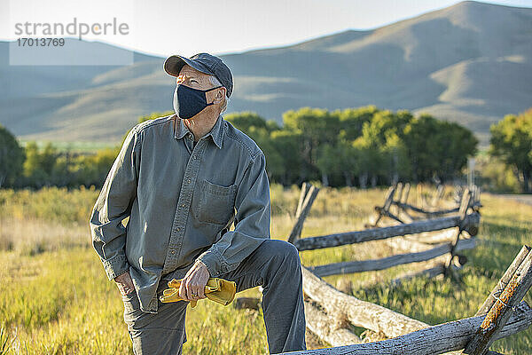 USA  Idaho  Bellevue  Farmer mit Gesichtsmaske lehnt an Zaun auf Feld