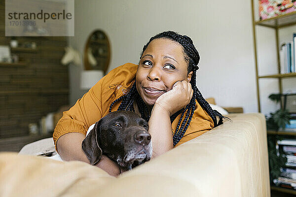 Frau liegend auf Sofa mit ihrem Hund