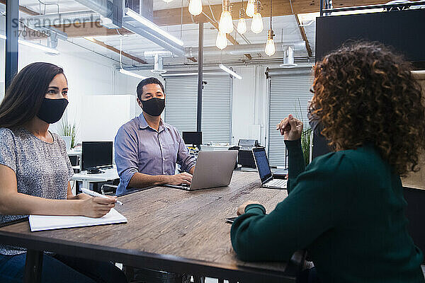 Menschen mit Gesichtsmasken bei einem Treffen im Büro