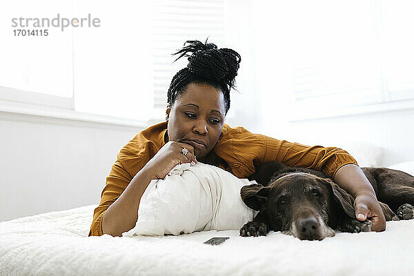 Traurige Frau auf dem Bett liegend mit Hund