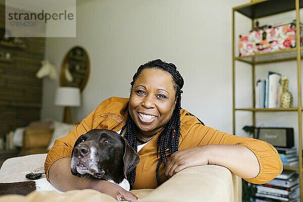 Porträt einer lächelnden Frau auf dem Sofa sitzend mit Hund