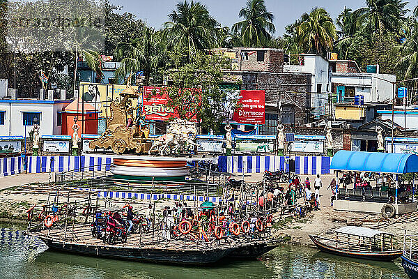 Stadt Murshidabad. Westbengalen  Indien. Um den Fluss zu überqueren  keine Brücke  sondern einfache Fähren auf einem Boot mit einem Bambusboden bedeckt angeordnet. In der Nähe des Flusses ein Tempel farbig.