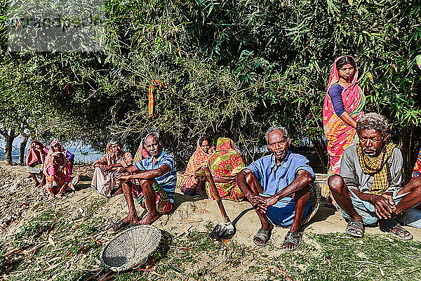 Dorf Matiari  Westbengalen  Indien.Matiari liegt am Ufer des Hooghly-Flusses  einem Nebenfluss des Ganges. Diese Arbeiter  die mit der Reinigung der Dorfstraßen beauftragt sind  machen eine Pause im Schatten der Bäume am Flussufer. Ein Besuch in Matiari ist auch eine Gelegenheit  ein authentisches indisches Dorf mit seiner Architektur und Lebensweise zu entdecken.