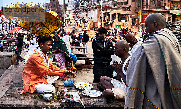 Varanasi (ex-Bénares)  Uttar Pradesh  Indien. Vor den rituellen Waschungen im Fluss vor der morgens aufgehenden Sonne sind einige bei einem Weisen  der die heiligen Texte auslegt. ohne sich von dem Trubel ringsum gestört zu fühlen.