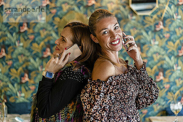Porträt von zwei Frauen  die sich mit ihren Smartphones unterhalten