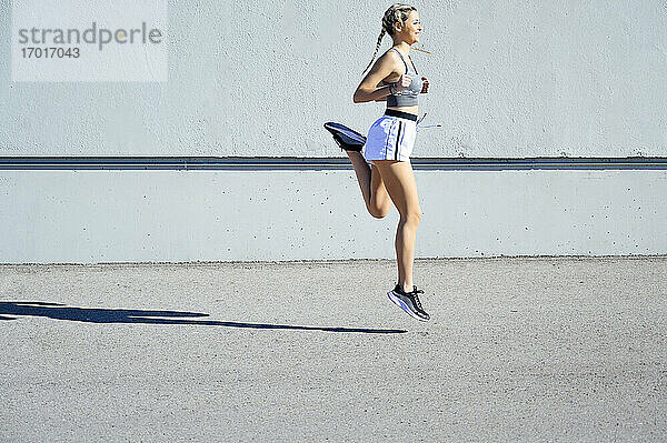 Junge Sportlerin läuft an einem sonnigen Tag gegen die Wand