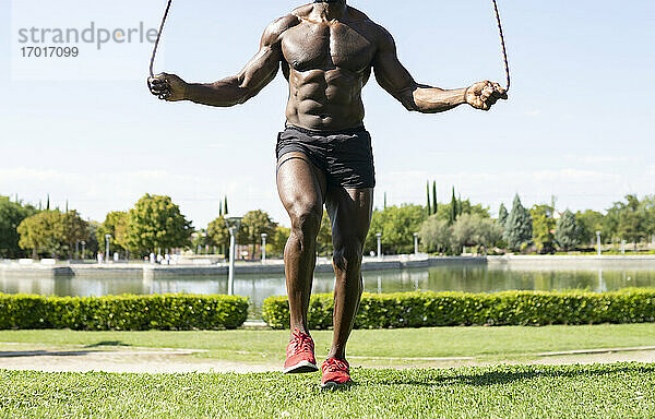 Afrikanischer männlicher Sportler bei einer Sprungübung im Park an einem sonnigen Tag