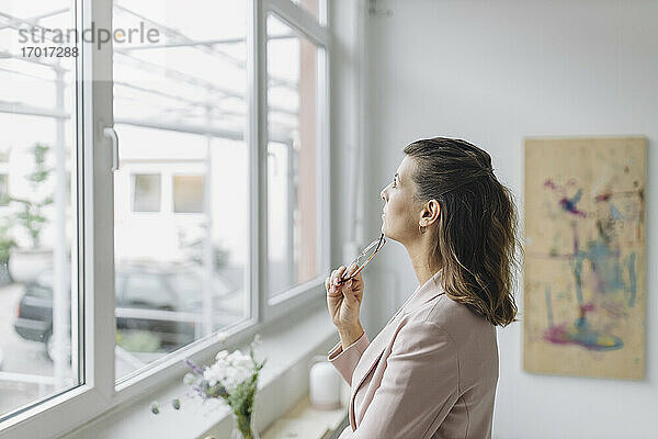 Geschäftsfrau schaut durch ein Fenster im Büro