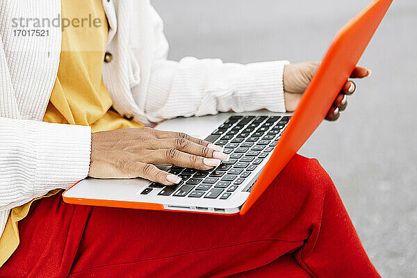 Frau  die im Freien sitzend am Laptop arbeitet