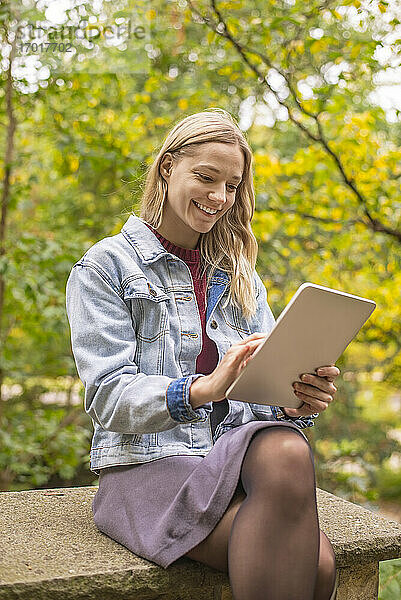 Lächelnde Frau mit digitalem Tablet in herbstlichem Park